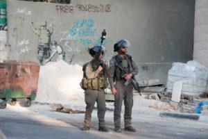Bethlehem, Occupied Palestinian Territories - November 20, 2012: Israeli soldiers occupy Bethlehem, West Bank, streets near a mural by the artist Banksy during Palestinian protests against Israeli attacks on Gaza.