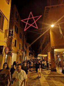 People at night and the Red Star in Via del Pratello, Bologna, Emilia Romagna