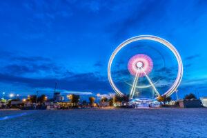 Spinning ferris wheel at sunrise blue hour in Rimini, Italy. Long exposure abstract image.